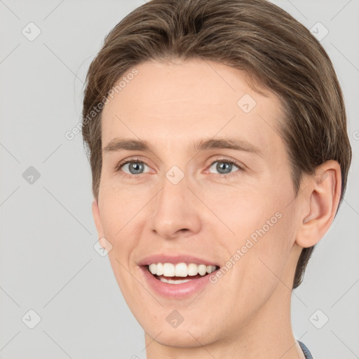 Joyful white young-adult male with short  brown hair and grey eyes