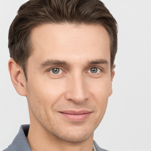 Joyful white young-adult male with short  brown hair and grey eyes