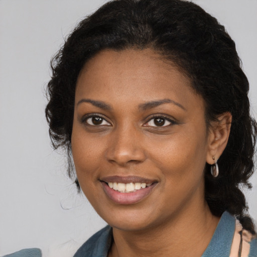 Joyful black young-adult female with long  brown hair and brown eyes