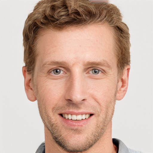 Joyful white young-adult male with short  brown hair and grey eyes