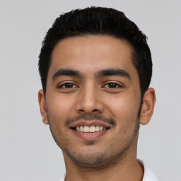 Joyful latino young-adult male with short  black hair and brown eyes