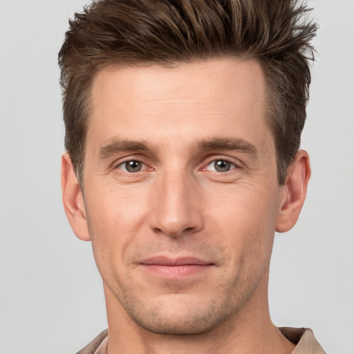 Joyful white young-adult male with short  brown hair and grey eyes