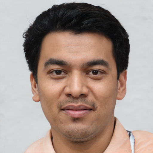 Joyful latino young-adult male with short  black hair and brown eyes