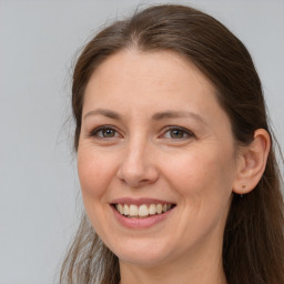 Joyful white adult female with long  brown hair and grey eyes