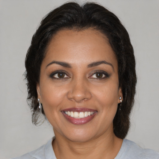 Joyful latino adult female with medium  brown hair and brown eyes