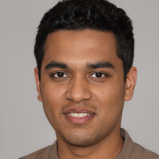 Joyful black young-adult male with short  black hair and brown eyes