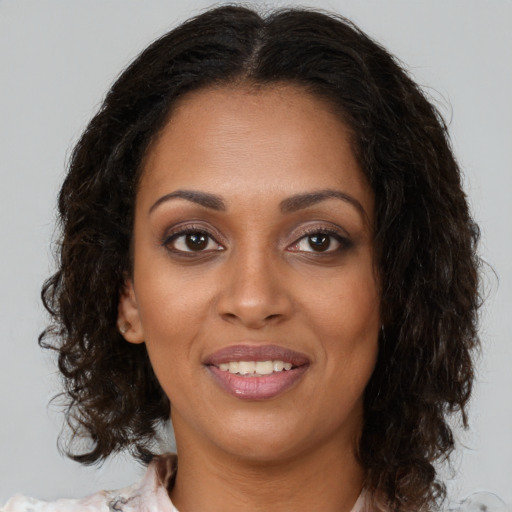 Joyful black young-adult female with long  brown hair and brown eyes