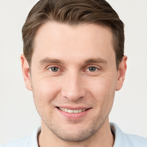 Joyful white young-adult male with short  brown hair and grey eyes