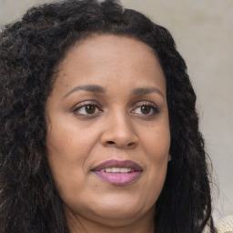 Joyful black adult female with long  brown hair and brown eyes