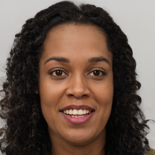 Joyful black young-adult female with long  brown hair and brown eyes