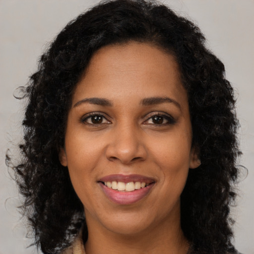 Joyful black young-adult female with long  brown hair and brown eyes