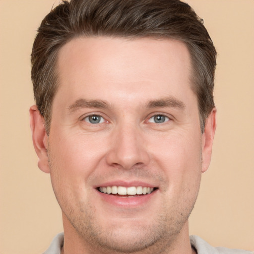 Joyful white young-adult male with short  brown hair and grey eyes