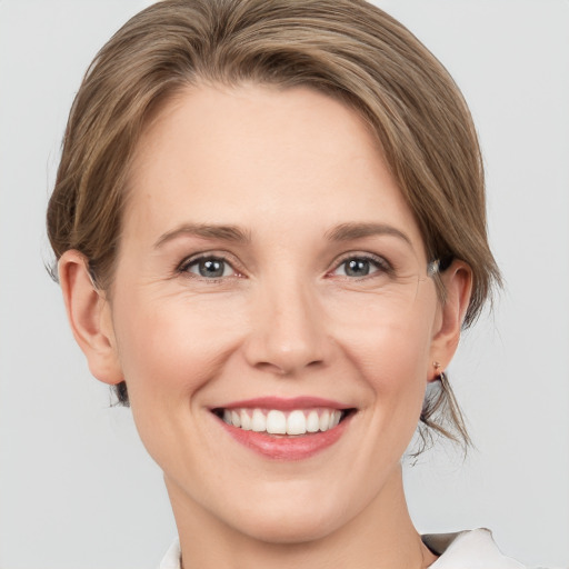 Joyful white young-adult female with medium  brown hair and grey eyes