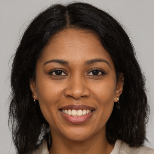 Joyful black young-adult female with long  brown hair and brown eyes