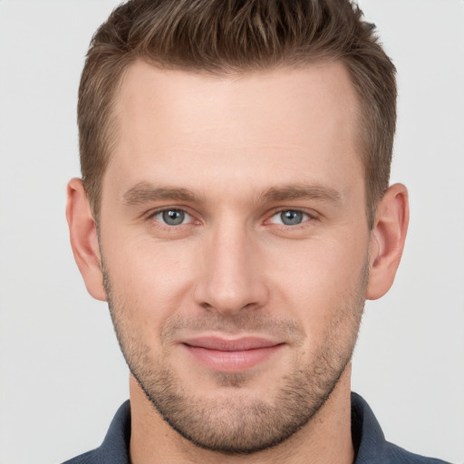 Joyful white young-adult male with short  brown hair and grey eyes