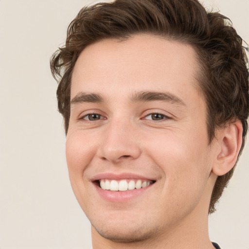 Joyful white young-adult male with short  brown hair and green eyes