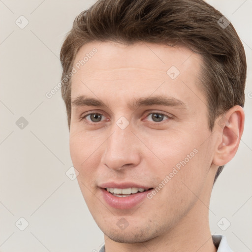 Joyful white young-adult male with short  brown hair and grey eyes