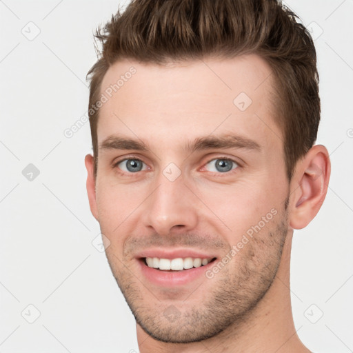 Joyful white young-adult male with short  brown hair and grey eyes