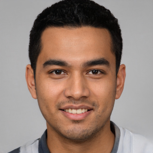 Joyful latino young-adult male with short  black hair and brown eyes