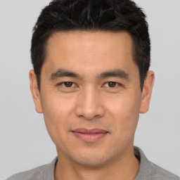 Joyful asian young-adult male with short  black hair and brown eyes