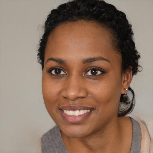 Joyful black young-adult female with short  black hair and brown eyes