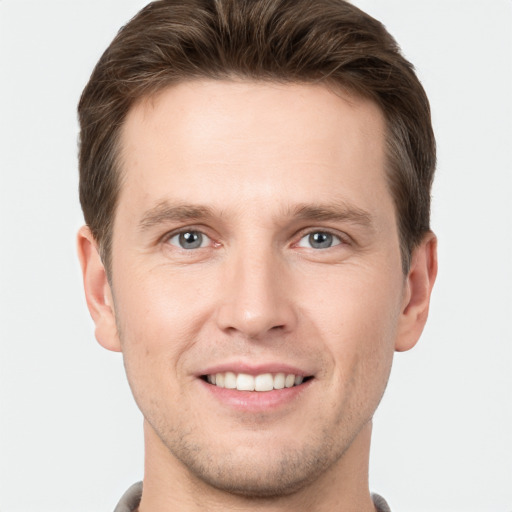 Joyful white young-adult male with short  brown hair and grey eyes