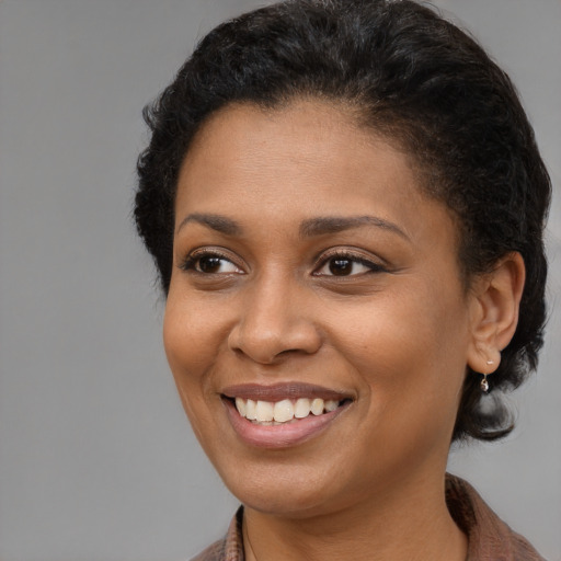 Joyful black young-adult female with short  brown hair and brown eyes