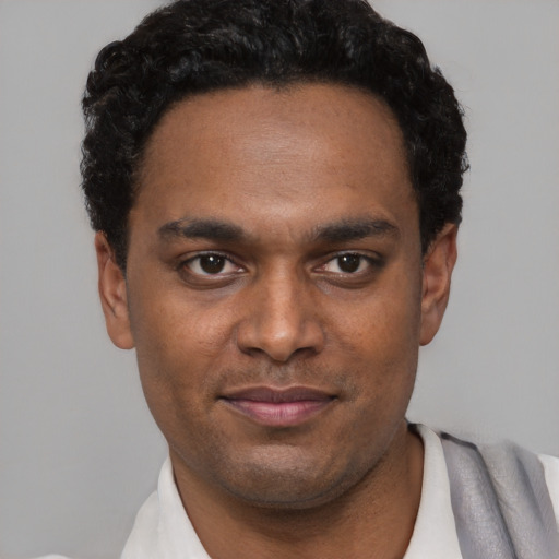 Joyful black young-adult male with short  black hair and brown eyes