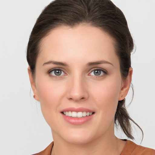 Joyful white young-adult female with medium  brown hair and grey eyes