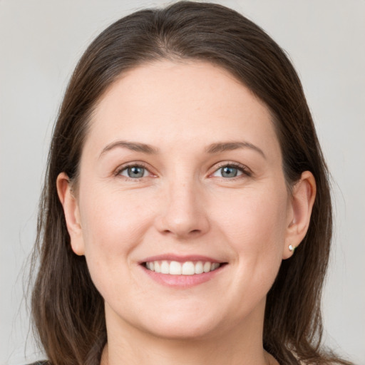 Joyful white young-adult female with long  brown hair and grey eyes