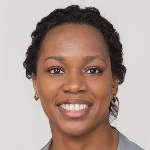 Joyful black young-adult female with short  black hair and brown eyes