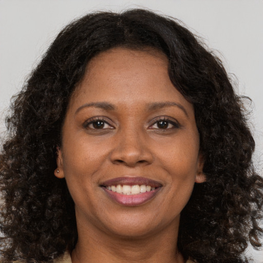 Joyful black young-adult female with long  brown hair and brown eyes