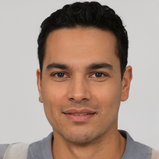 Joyful latino young-adult male with short  black hair and brown eyes