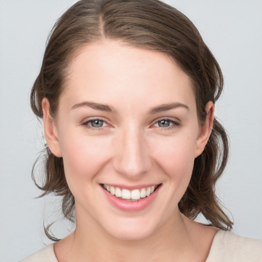 Joyful white young-adult female with medium  brown hair and grey eyes