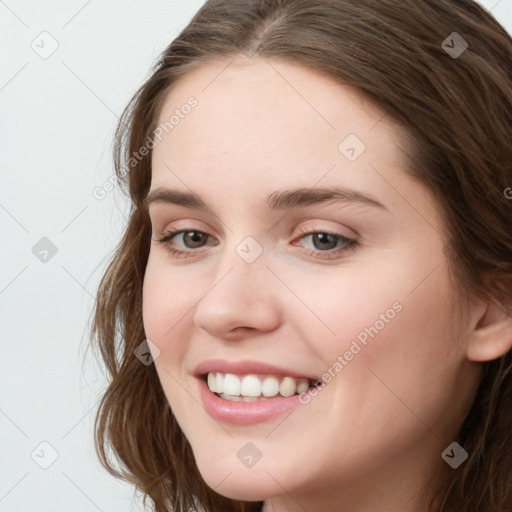 Joyful white young-adult female with long  brown hair and grey eyes