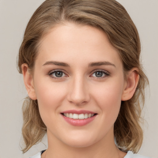 Joyful white young-adult female with medium  brown hair and grey eyes