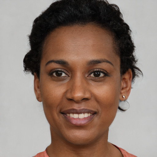 Joyful black young-adult female with short  black hair and brown eyes