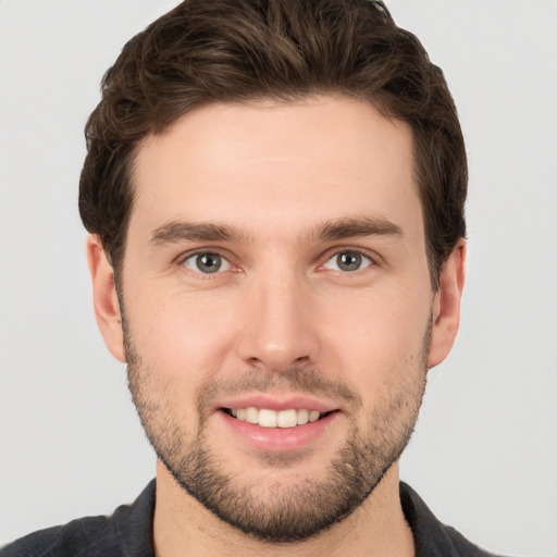 Joyful white young-adult male with short  brown hair and grey eyes