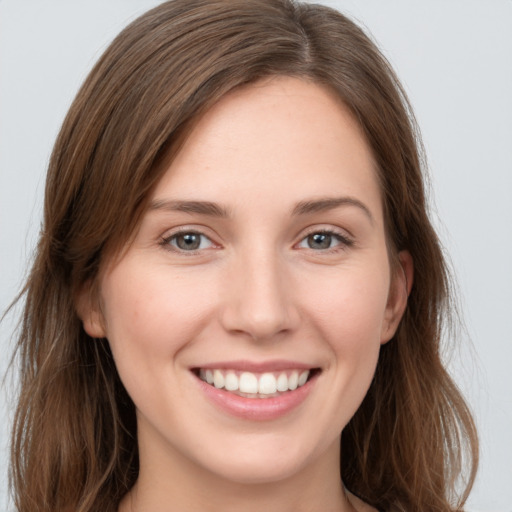 Joyful white young-adult female with long  brown hair and grey eyes