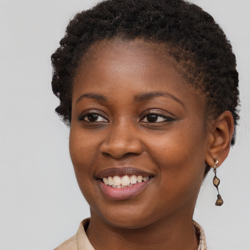Joyful black young-adult female with long  brown hair and brown eyes