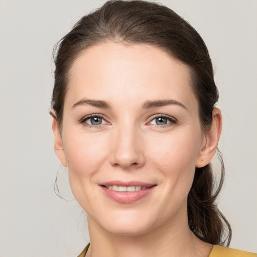 Joyful white young-adult female with medium  brown hair and grey eyes