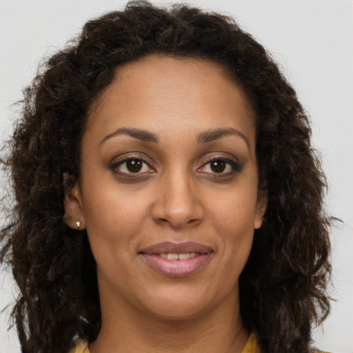 Joyful black young-adult female with long  brown hair and brown eyes