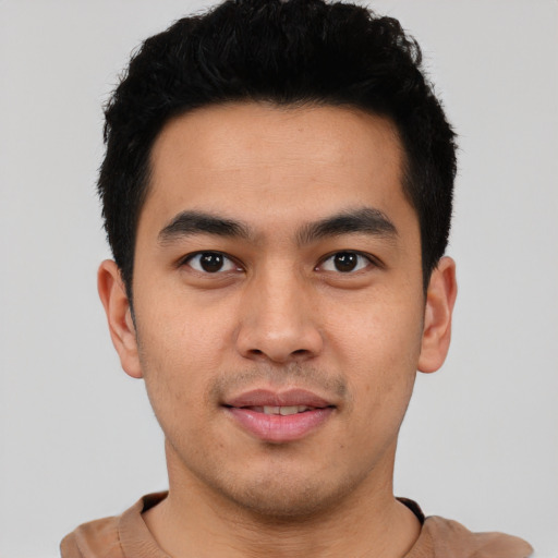 Joyful latino young-adult male with short  black hair and brown eyes