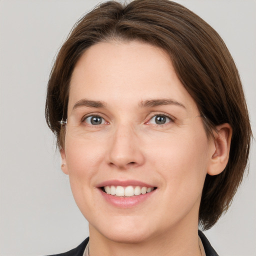 Joyful white young-adult female with medium  brown hair and grey eyes