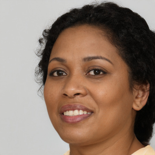 Joyful black young-adult female with long  brown hair and brown eyes