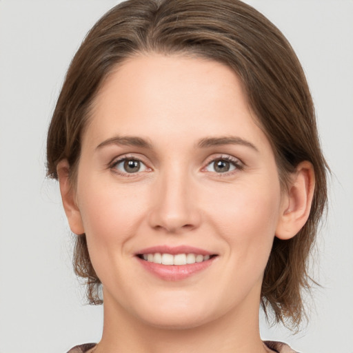 Joyful white young-adult female with medium  brown hair and grey eyes