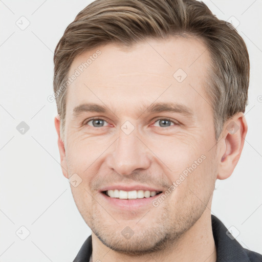 Joyful white young-adult male with short  brown hair and grey eyes