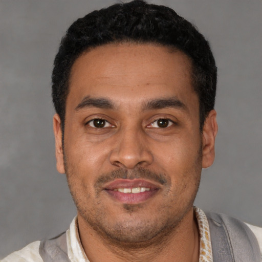 Joyful latino young-adult male with short  black hair and brown eyes