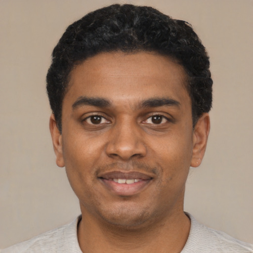Joyful black young-adult male with short  black hair and brown eyes