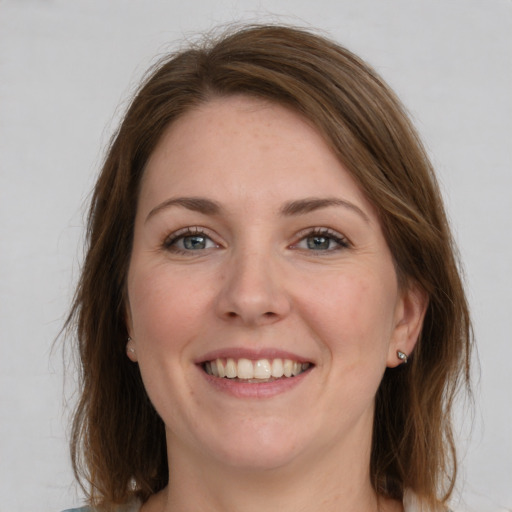 Joyful white young-adult female with medium  brown hair and grey eyes